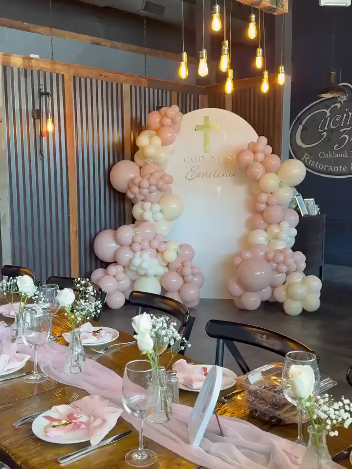 Blush and ivory organic balloon garland around a cream arch for a baptism at Cucina 347 in Oakland, NJ